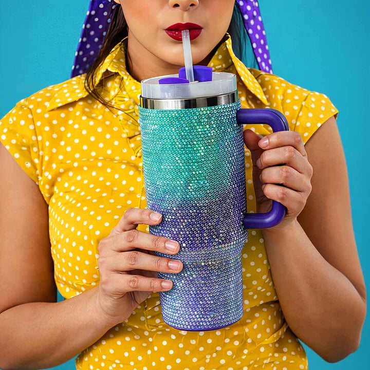 Woman sipping from a blue-purple rhinestone bling tumbler with straw by TPC Gifts