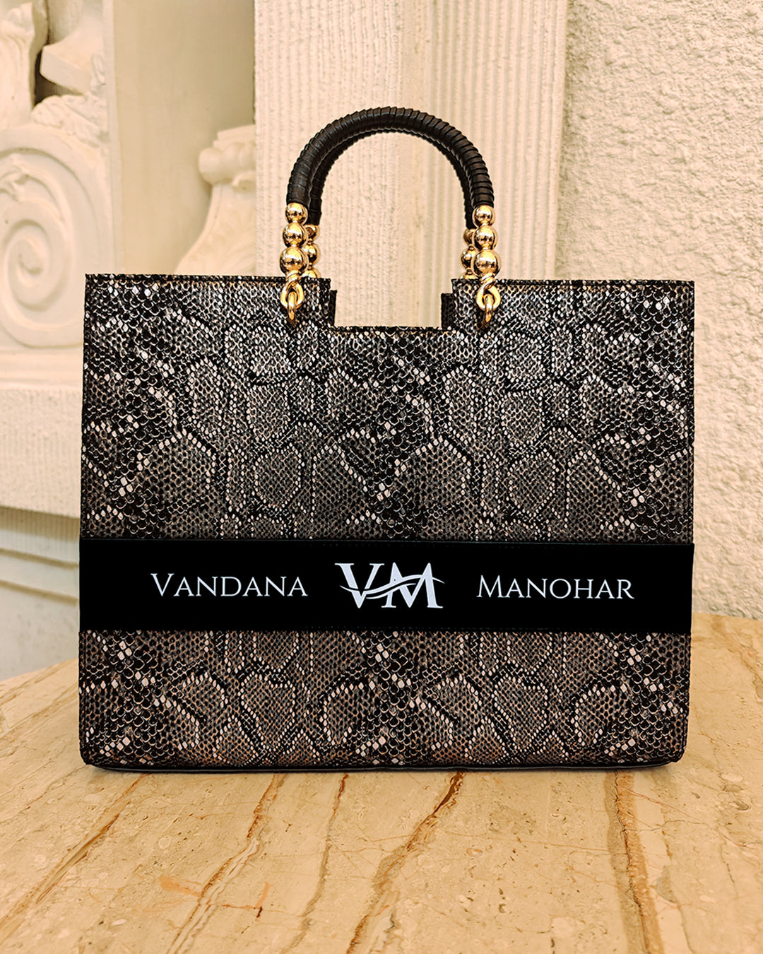 Personalized black tote bag by TPC Gifts with gold accents on a marble surface, featuring the name Vandana Manohar
