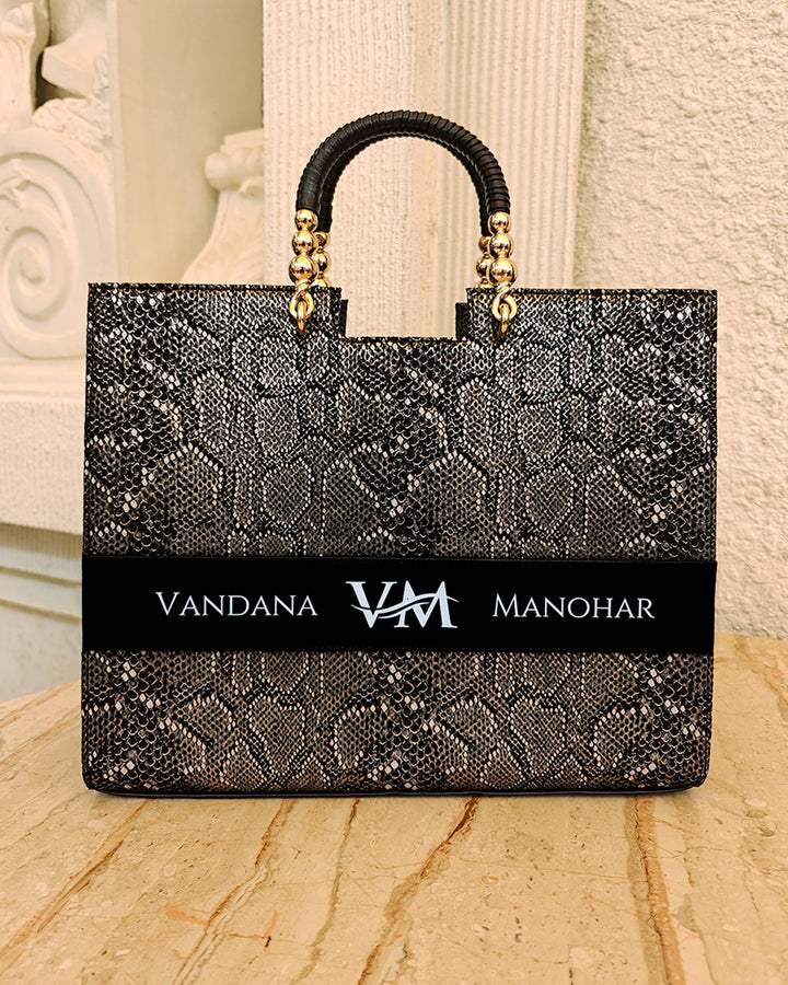 Personalized black tote bag by TPC Gifts with gold accents on a marble surface, featuring the name Vandana Manohar
