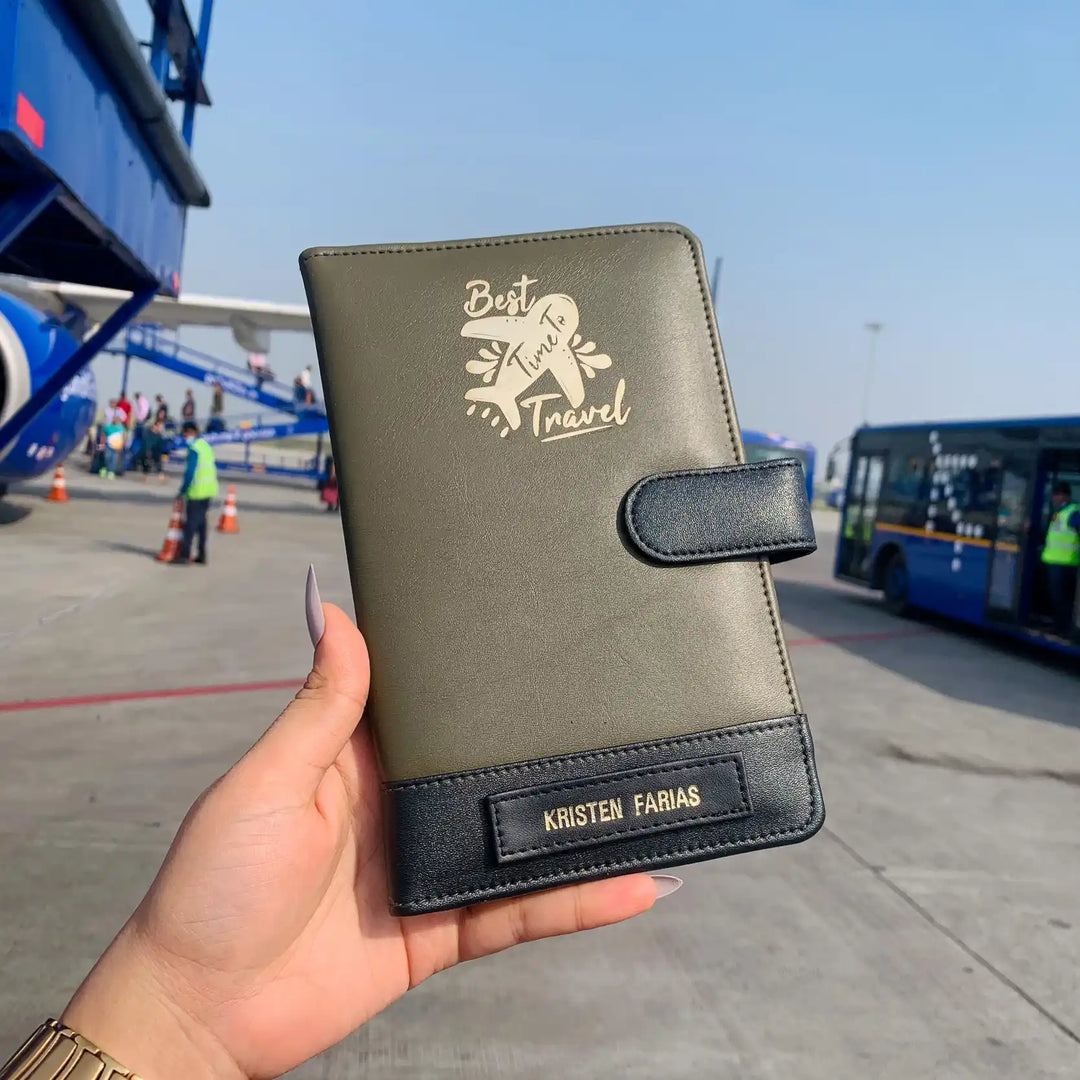 Olive Black dual tone  travel organiser wallet held by a hand with an airport in the background - TPC Gifts