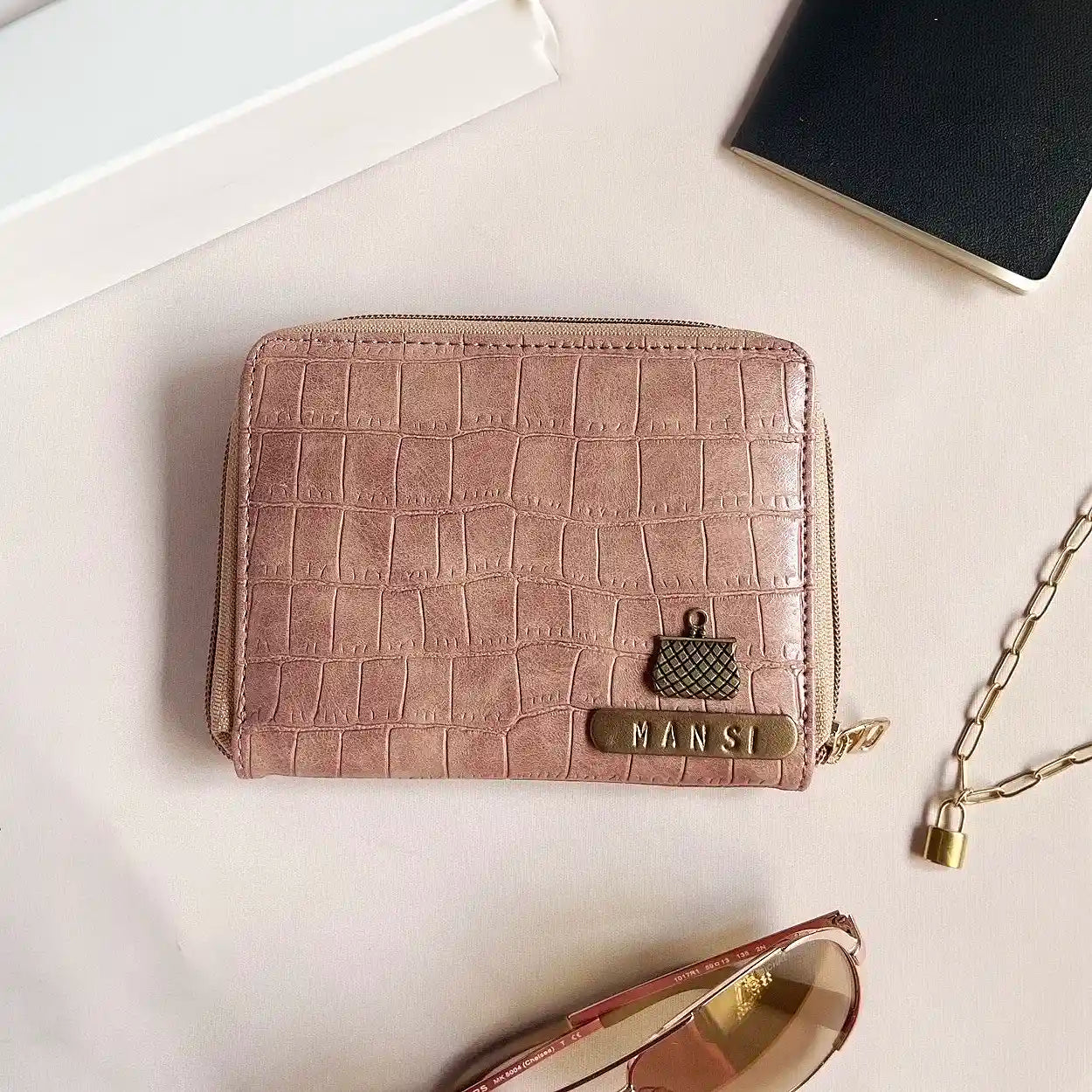 Onion Pink croco  textured wallet with 'MANSI' name on a light surface.