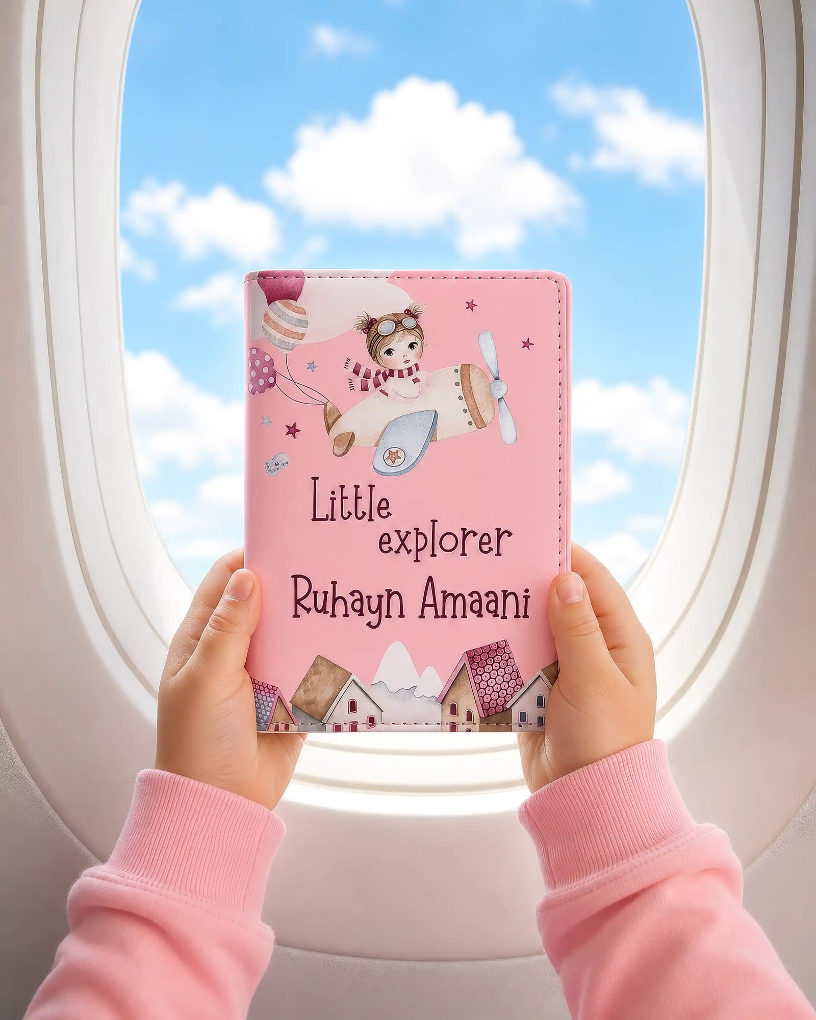 Pink travel wallet with airplane design held by a child against an airplane window view.