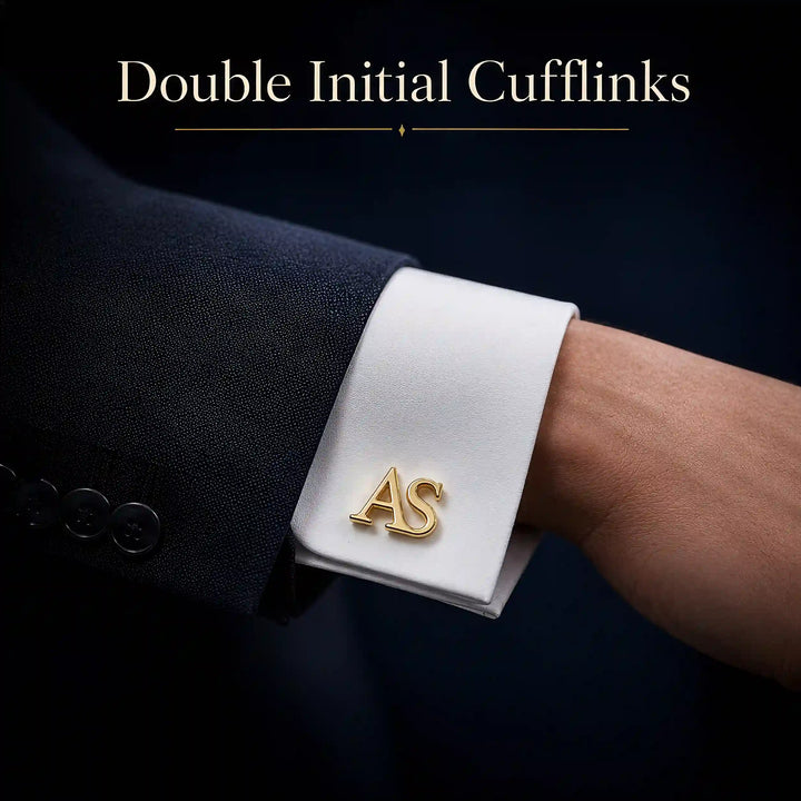 A close-up of a white dress shirt cuff with a gold double initial cufflink engraved with the letters &