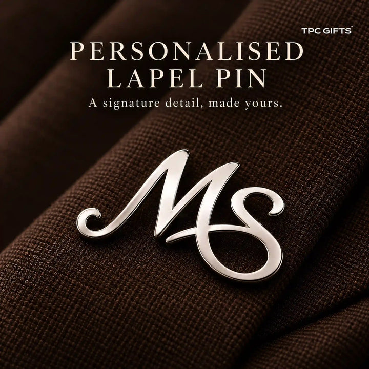 Personalised two initial silver tone lapel pin close up on brown fabric