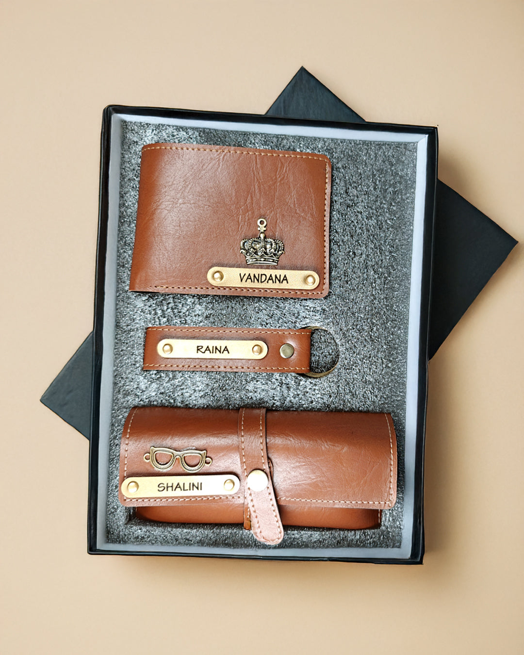 Set of brown leather wallets with nameplates in a black box on a beige background