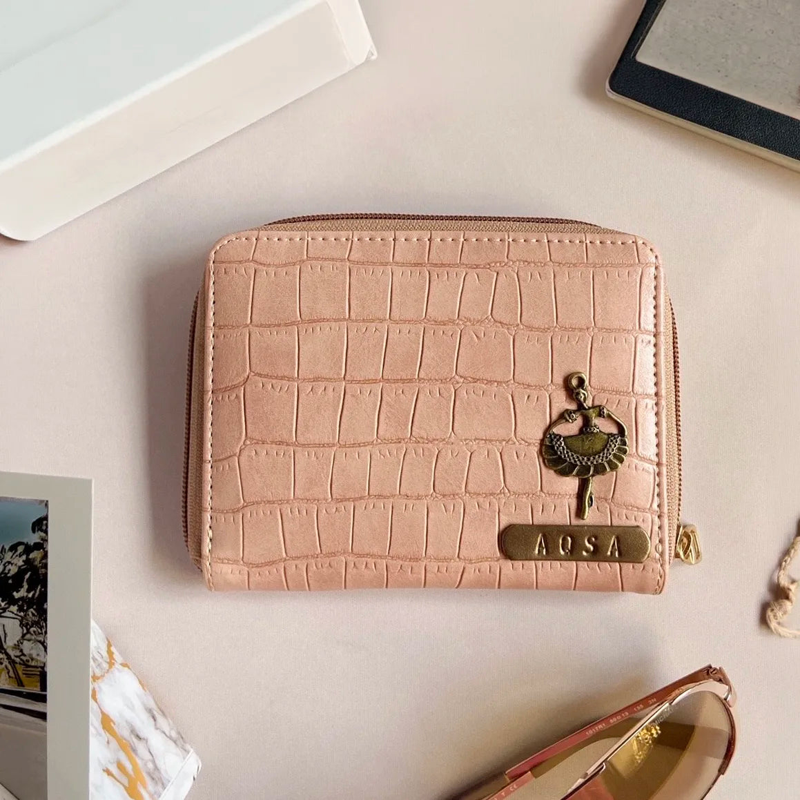 Salmon Pink croco textured wallet with 'AQSA' on a light surface.