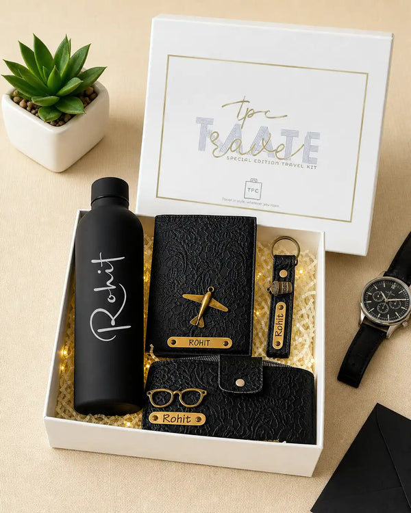 Gift set with black water bottle, passport cover , keychain, and sunglass  cover with travelmate box a beige surface with a plant and card - TPC Gifts
