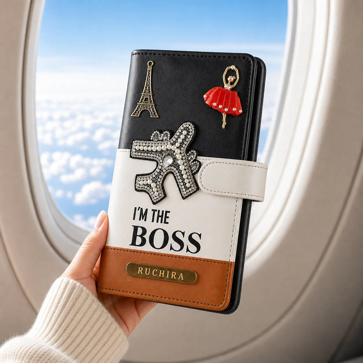 Hand holding a wallet with decorative elements and 'I'm the Boss' text, airplane window in background- TPC Gifts