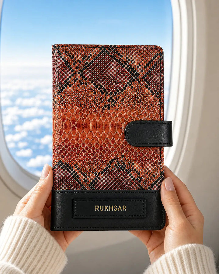 Person holding a tangerine orange and black patterned genuine leather travel organiser with &