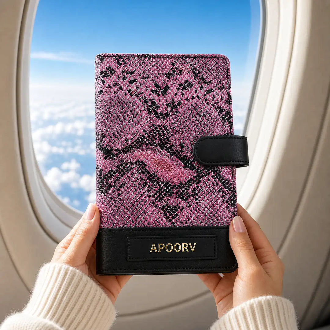Pink and black patterned genuine leather travel organiser held by hands with airplane window in background - TPC Gifts