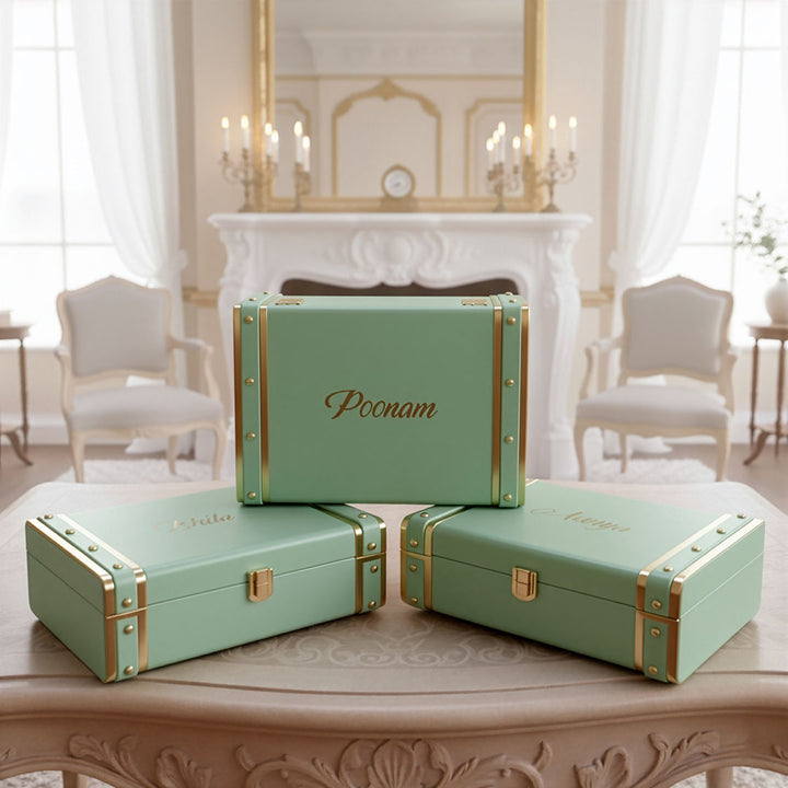 Set of green trunk boxes with gold accents on a table in a elegant room by TPC Gifts