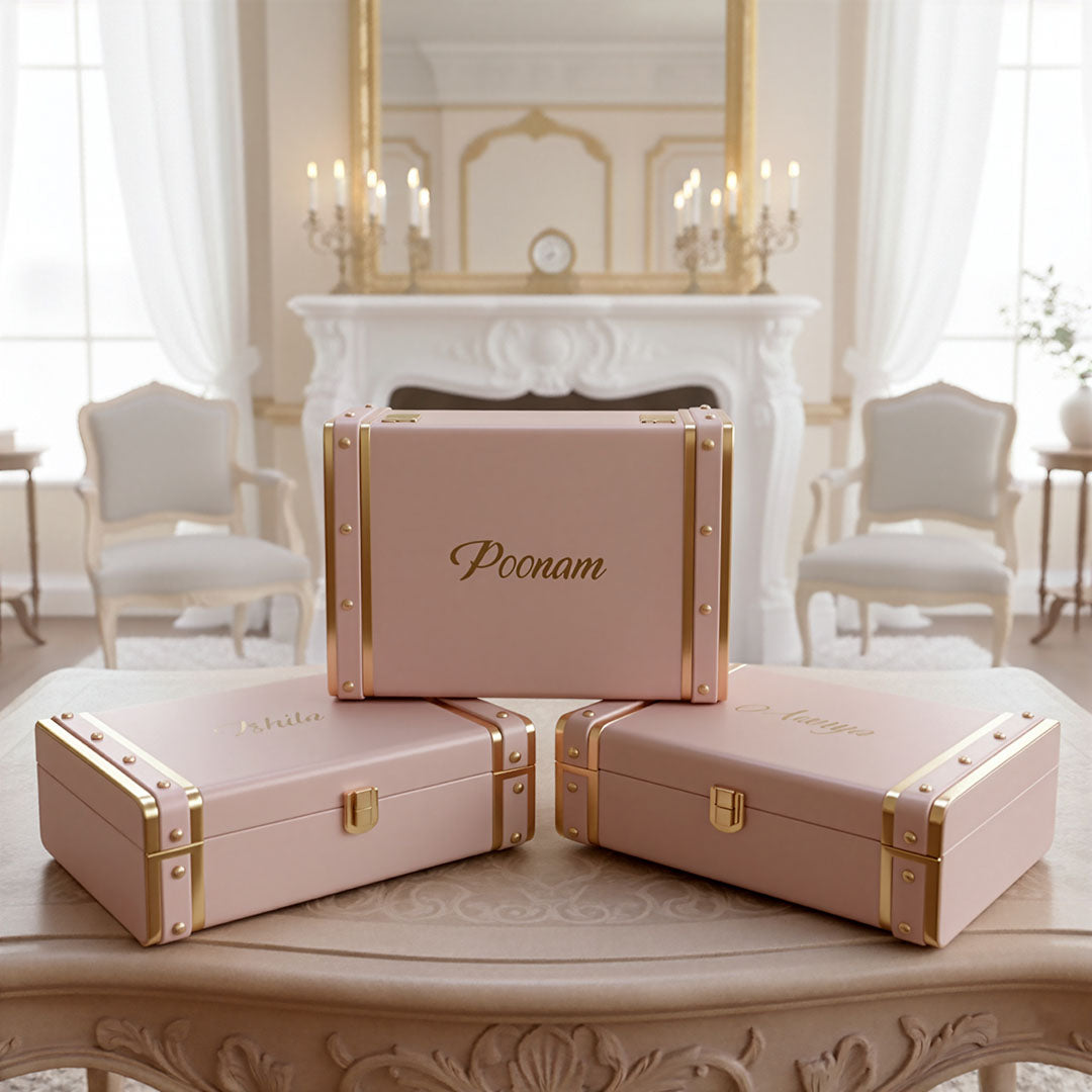 Set of pink trunk boxes with gold accents on a decorative table in an elegant room by TPC Gifts
