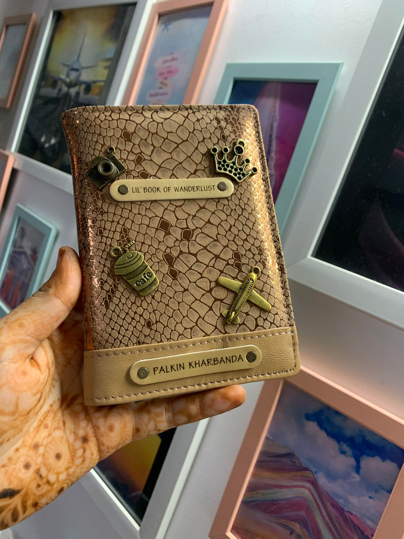 Personalized passport cover from TPC Gifts which is a Personalized Passport Cover in golden colour, personalised with name and 4 charms and 1 quotes in a flat lay view.