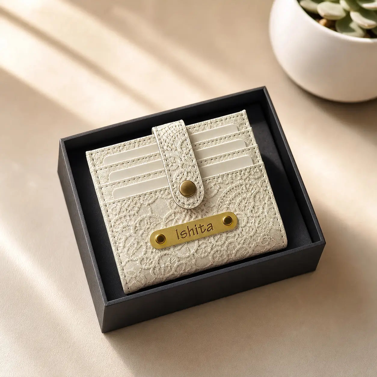 White textured cardholder by tpc gifts with gold accents in a black box on a beige surface.