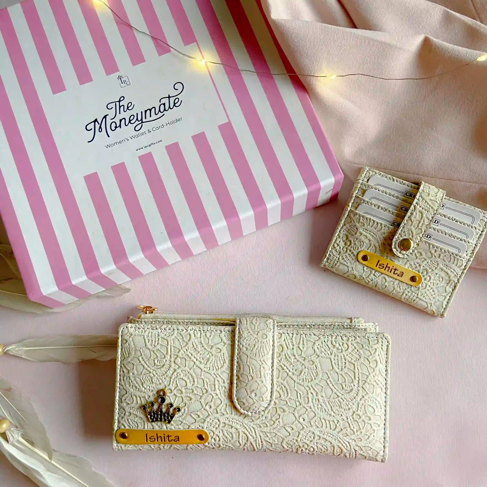 Two lace-patterned wallets with 'The Moneymate' packaging on a pink background.