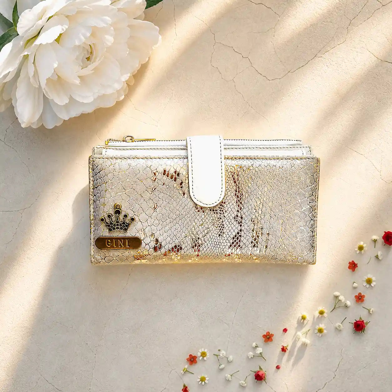 Golden textured wallet with a brand logo on a light background with flowers by tpc gifts personalized wallet for women