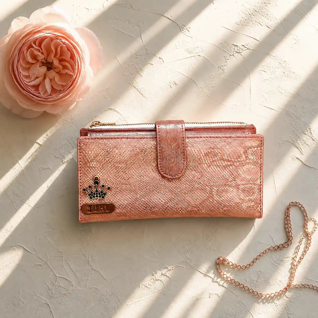Rose gold wallet with chain on a textured surface with a pink flower by tpc gifts personalized wallet for women
