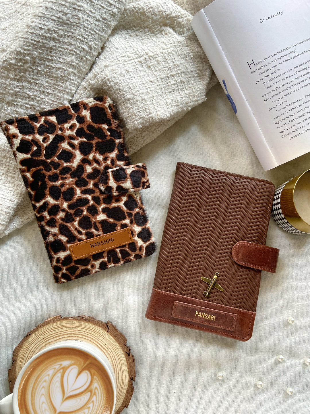 Two travel organizers, one with a ziggy caramel brown color and another with a animal print, placed on a surface with a cup of coffee and a book at backgroud setup from TPC Gifts