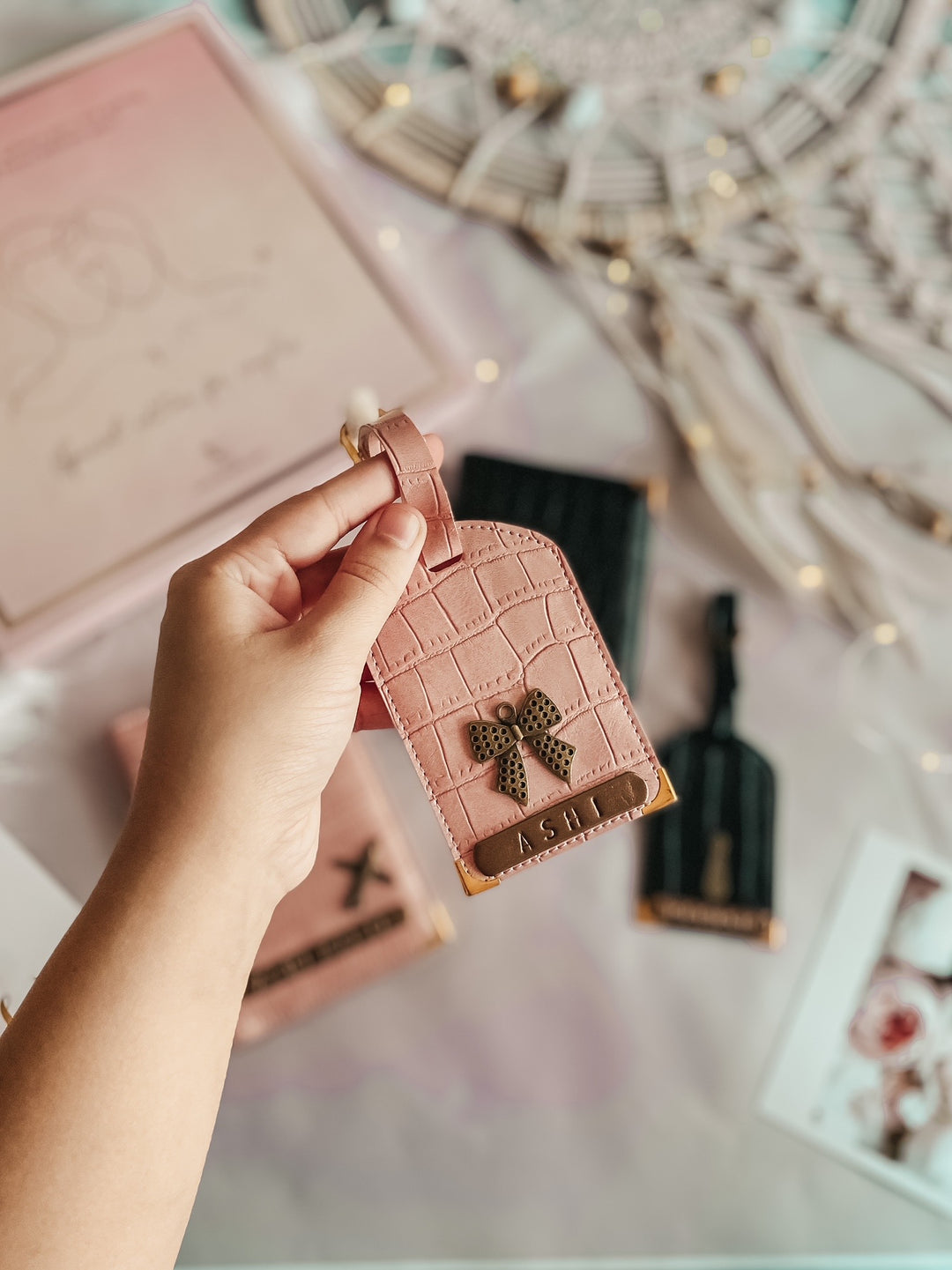 A pink textured luggage tag with a personalized name tag and a buckled strap on a marble surface.