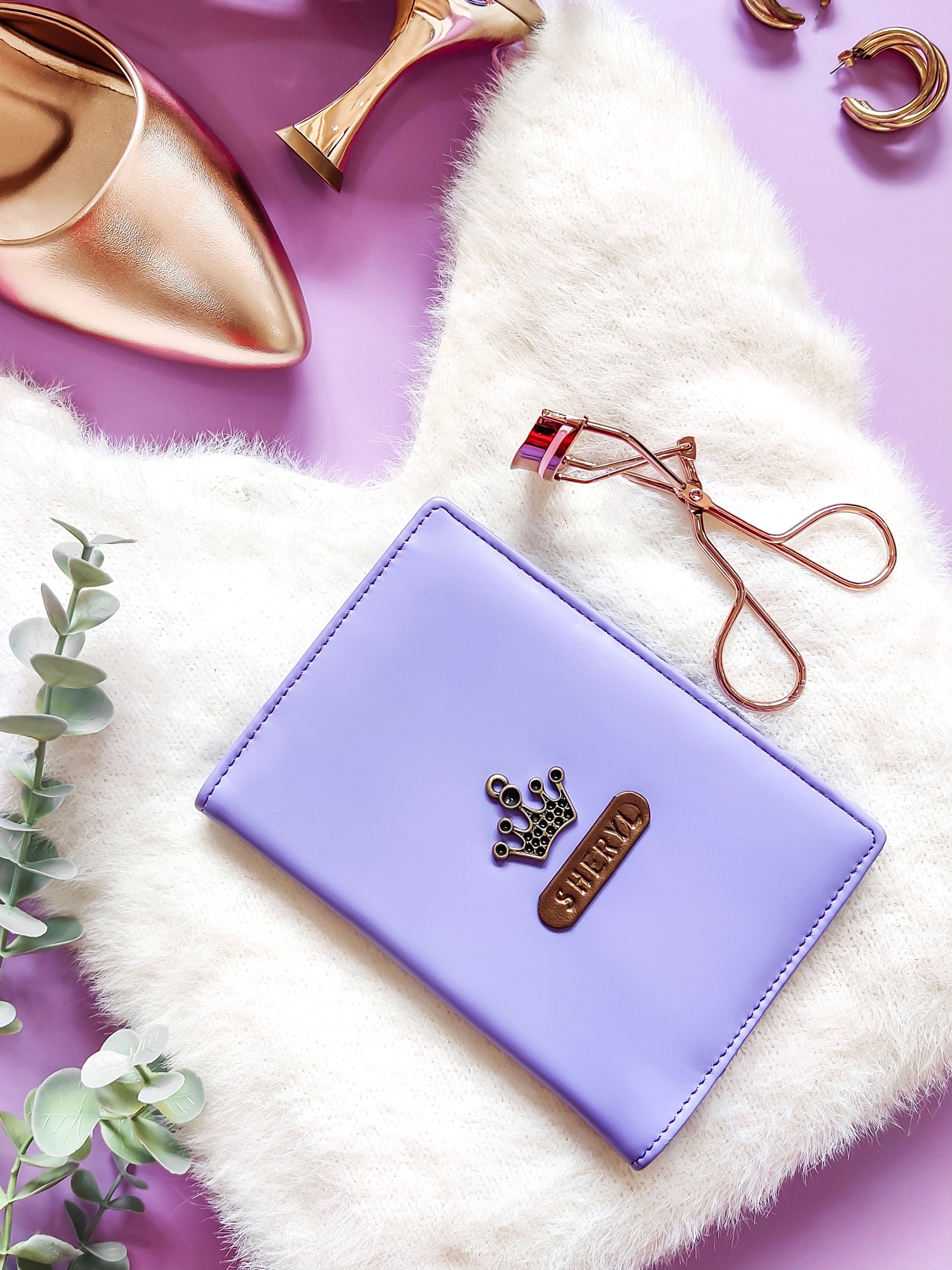 A purple vegan leather passport cover with a faux fur lining, a passport partially inserted, and a name tag on the cover, placed on a purple surface with a decorative item in the background.