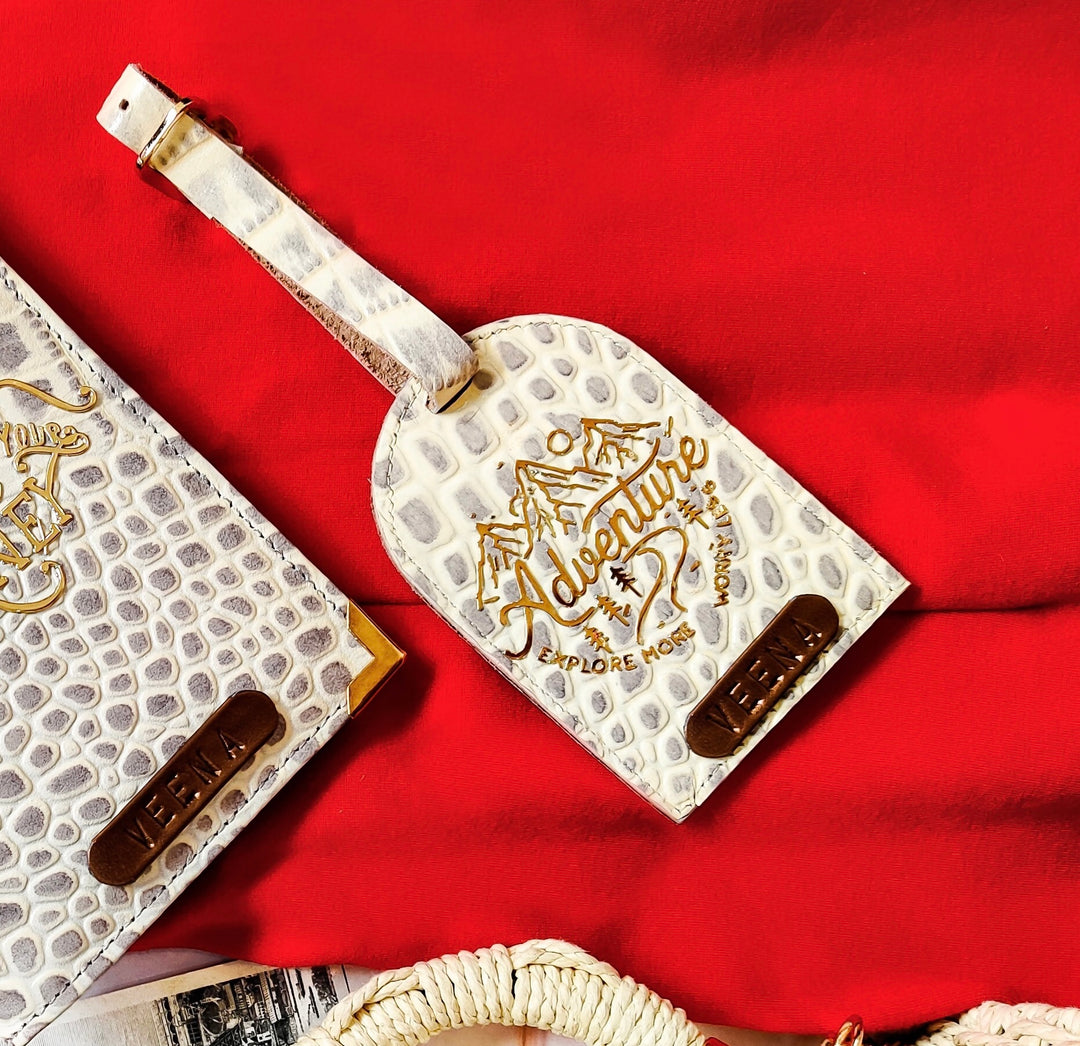 Leather Luggage Tag by TOPC Gifts. White in colour with adventure sticker on it and even the matching passport cover is there at the side. it is basically a passport cover and luggage tag set